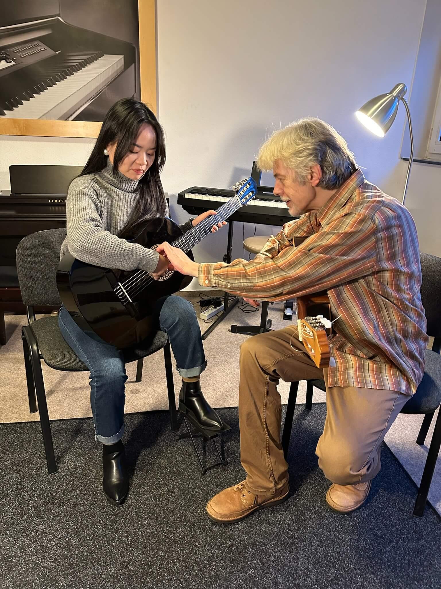 Gitarrenschülerin und Lehrer im Unterricht an der Musikschule
